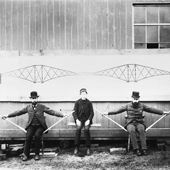Photograph of two men, who on the left and right of the photograph represent two piers, stick between them represents the central girder, and the young man sitting in the middle represents the load being placed on the central girder, 1887 (Crown Copyright, National Records of Scotland, BR/FOR/4/34/161)