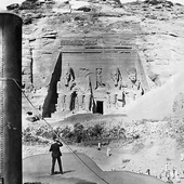 Photograph of the view of the Great Temple at Abu Simbel showing the colossi of Ramesses II taken from the deck of a steam boat, a crowd of people look on as a man standing just fore of the funnel takes a picture, Nile Pleasure Cruise, 1898 (Crown Copyright, National Records of Scotland, GD268/1055/53e)