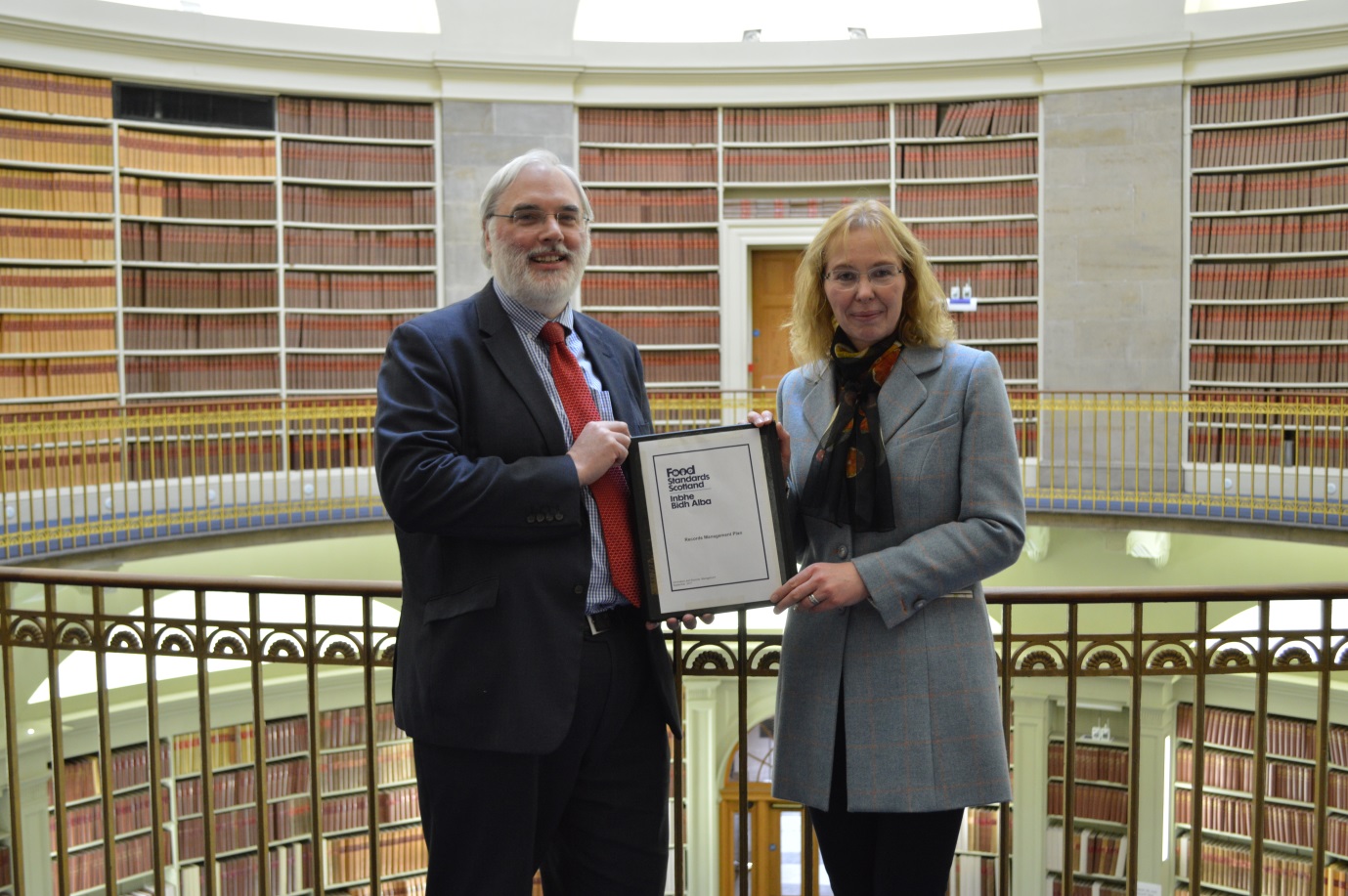 Tim Ellis, Keeper of the Records of Scotland, presenting Elspeth Macdonald, Deputy Chief Executive at Food Standards Scotland, with agreed the Records Management Plan 